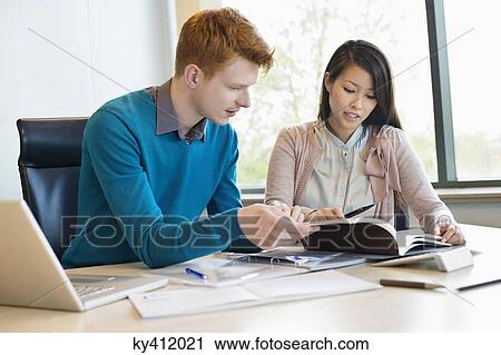 Businessman examining documents with his secretary View Large Photo Image Stock Image - Businessman examining documents with his secretary. Fotosearch