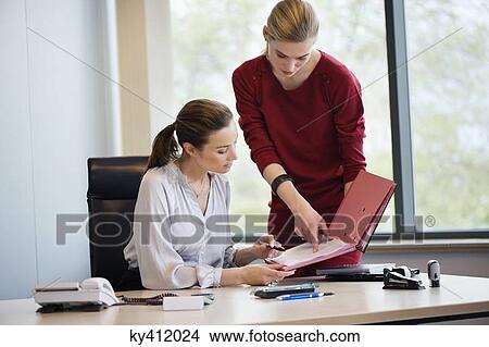 Businesswoman signing documents with her secretary View Large Photo Image Picture - Businesswoman signing documents with her secretary. Fotosearch