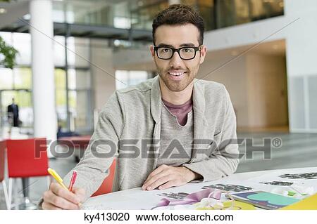 Stock Image - Male fashion designer working in an office. Fotosearch