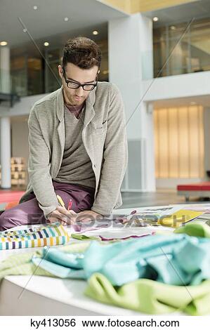 Stock Photograph - Male fashion designer working in an office. Fotosearch