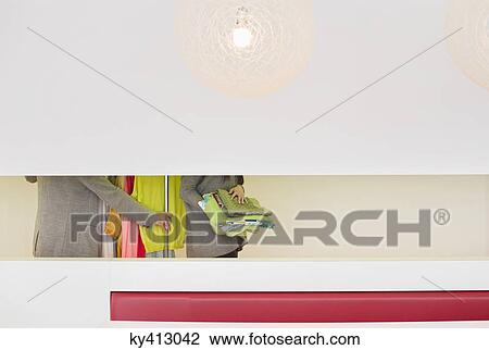 Stock Image - Mid section view of fashion designers with clothes rail in a corridor. Fotosearch