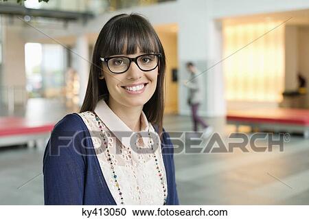Stock Image - Portrait of a businesswoman smiling in an office. Fotosearch