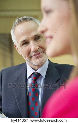 Business executives discussing in an office corridor View Large Photo Image Stock Photo - Business executives discussing in an office corridor. Fotosearch