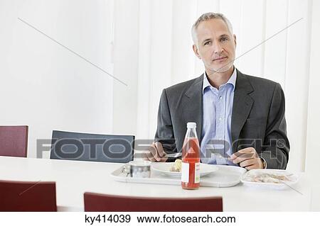 Stock Photo - Businessman having lunch in the office. Fotosearch