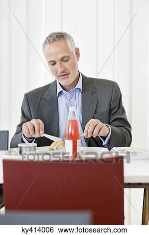 Businessman having lunch in the office View Large Photo Image Stock Photograph - Businessman having lunch in the office. Fotosearch