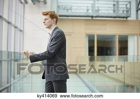 Businessman looking through glass window in a corridor View Large Photo Image Stock Photo - Businessman looking through glass window in a corridor. Fotosearch