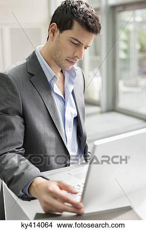 Picture - Businessman working on a laptop in an office. Fotosearch