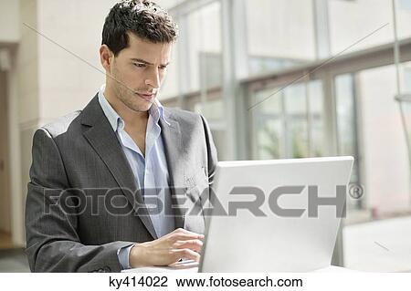 Businessman working on a laptop in an office View Large Photo Image Stock Image - Businessman working on a laptop in an office. Fotosearch
