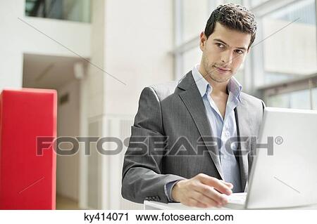 Businessman working on a laptop in an office View Large Photo Image Stock Image - Businessman working on a laptop in an office. Fotosearch