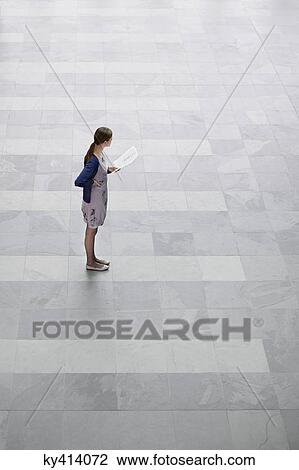 Businesswoman holding documents and standing in an office lobby View Large Photo Image Stock Image - Businesswoman holding documents and standing in an office lobby. Fotosearch