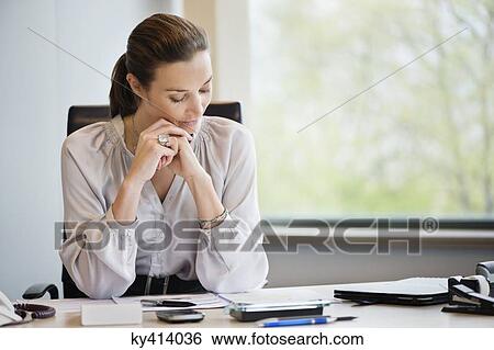 Stock Photograph - Businesswoman reading documents in an office. Fotosearch
