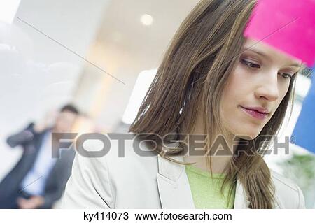 Stock Photo - Businesswoman sticking memo notes on glass in an office. Fotosearch - Search Stock Images, Poster Photographs, Pictures, and Clip Art Photos