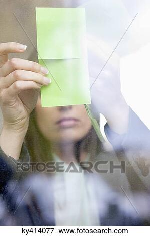 Businesswoman sticking memo notes on glass in an office View Large Photo Image Stock Photo - Businesswoman sticking memo notes on glass in an office. Fotosearch