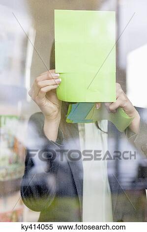Stock Photography - Businesswoman sticking memo notes on glass in an office. Fotosearch