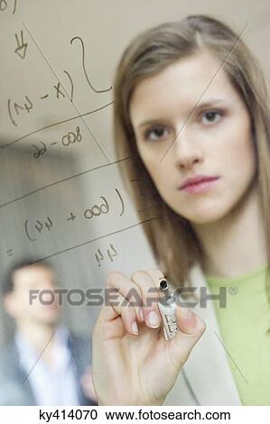 Stock Image - Businesswoman writing numeric figures on a glass surface. Fotosearch
