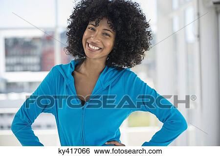 Stock Photograph - Portrait of a smiling woman standing with hands on hips. Fotosearch