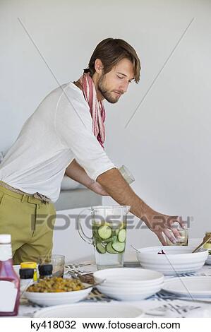 Stock Image - Man arranging a dining table. Fotosearch