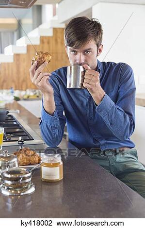 Man having breakfast at a kitchen counter View Large Photo Image Stock Image - Man having breakfast at a kitchen counter. Fotosearch