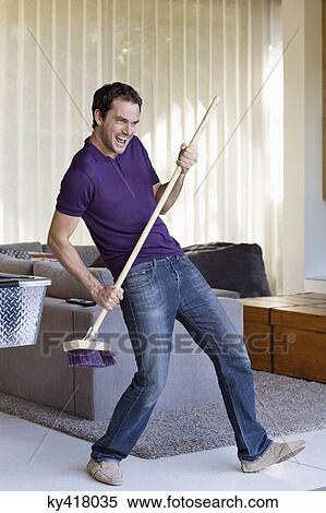 Stock Photography - Man holding a mop as a guitar. Fotosearch