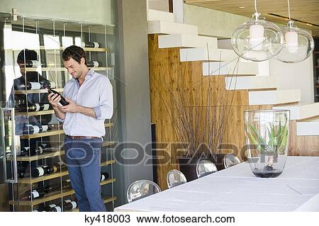 Man looking at a wine bottle View Large Photo Image Stock Image - Man looking at a wine bottle. Fotosearch