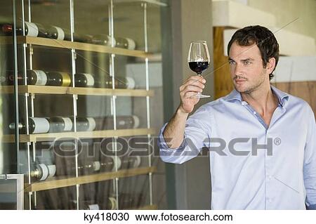 Man looking at red wine in a wineglass View Large Photo Image Stock Image - Man looking at red wine in a wineglass. Fotosearch