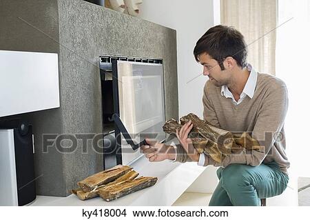 Man putting firewood into a fireplace View Large Photo Image Picture - Man putting firewood into a fireplace. Fotosearch