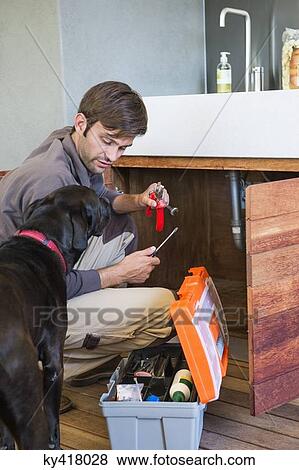 Stock Photo - Man repairing a kitchen sink. Fotosearch