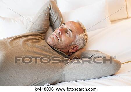 Man resting on the bed in a hotel room View Large Photo Image Stock Photograph - Man resting on the bed in a hotel room. Fotosearch