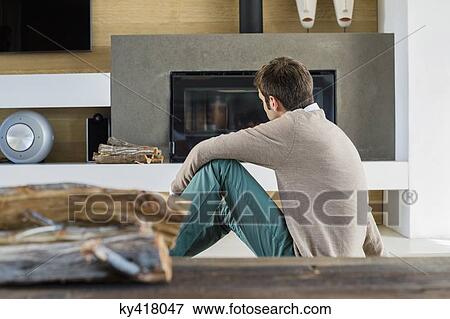 Man sitting in front of a fireplace at home View Large Photo Image Stock Photo - Man sitting in front of a fireplace at home. Fotosearch