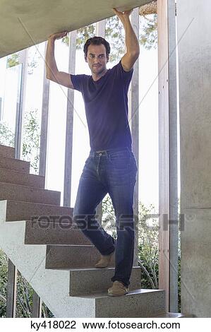 Stock Image - Man standing on steps at home. Fotosearch