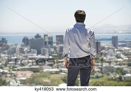 Man standing on the terrace looking at a city View Large Photo Image Stock Image - Man standing on the terrace looking at a city. Fotosearch
