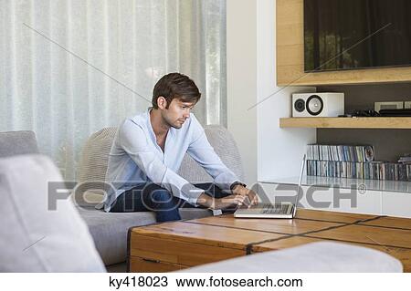 Man using a laptop at home View Large Photo Image Stock Image - Man using a laptop at home. Fotosearch