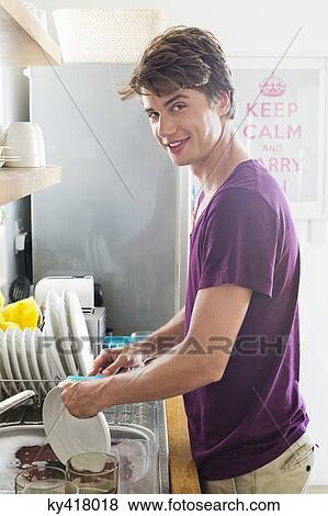 Man washing dishes in his kitchen View Large Photo Image Stock Photo - Man washing dishes in his kitchen. Fotosearch