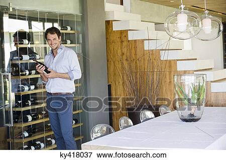 Stock Photo - Portrait of a smiling man holding a wine bottle. Fotosearch