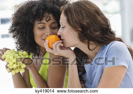 Picture - Close-up of two female friends smelling fruits. Fotosearch