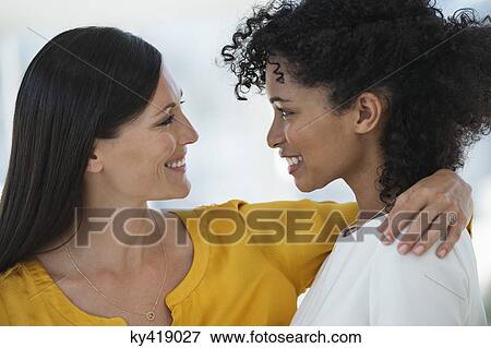 Close-up of two female friends smiling at each other View Large Photo Image Stock Photo - Close-up of two female friends smiling at each other. Fotosearch