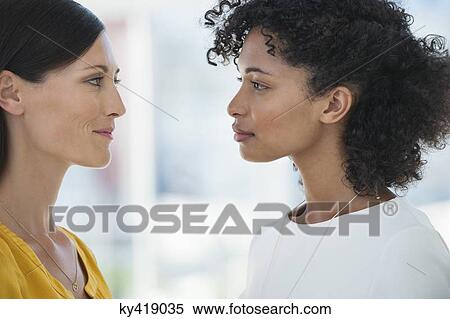 Close-up of two female friends smiling at each other View Large Photo Image Stock Photography - Close-up of two female friends smiling at each other. Fotosearch