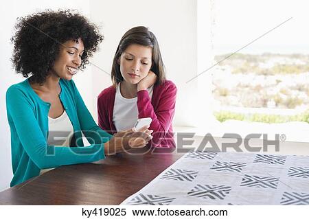 Stock Photography - Friends looking at a mobile phone. Fotosearch