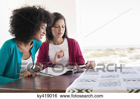Friends reading a magazine View Large Photo Image Stock Photograph - Friends reading a magazine. Fotosearch
