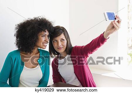 Friends taking picture of themselves with a mobile phone View Large Photo Image Stock Photo - Friends taking picture of themselves with a mobile phone. Fotosearch