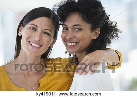 Stock Image - Portrait of two female friends smiling together. Fotosearch