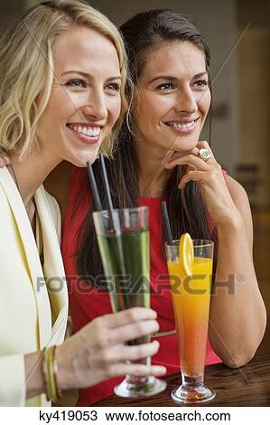 Two female friends enjoying drinks in a restaurant View Large Photo Image Stock Image - Two female friends enjoying drinks in a restaurant. Fotosearch