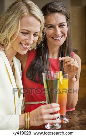 Two female friends enjoying drinks in a restaurant View Large Photo Image Stock Photo - Two female friends enjoying drinks in a restaurant. Fotosearch