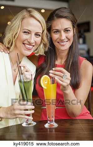 Two female friends enjoying drinks in a restaurant View Large Photo Image Stock Photography - Two female friends enjoying drinks in a restaurant. Fotosearch