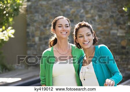 Two female friends smiling together View Large Photo Image Stock Image - Two female friends smiling together. Fotosearch