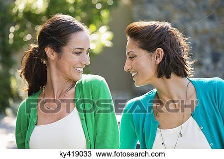 Two female friends smiling together View Large Photo Image Stock Image - Two female friends smiling together. Fotosearch