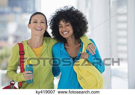 Stock Photo - Two happy female friends carrying gym bags. Fotosearch