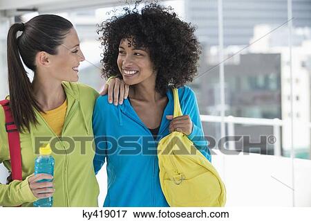 Two happy female friends carrying gym bags View Large Photo Image Stock Photo - Two happy female friends carrying gym bags. Fotosearch