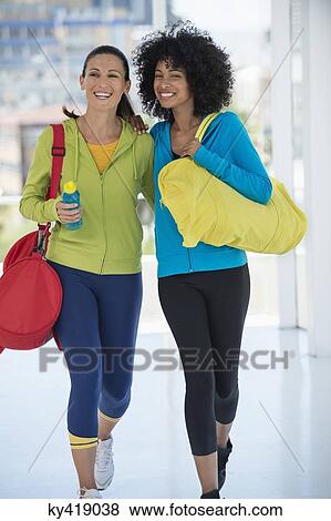 Two happy female friends carrying gym bags View Large Photo Image Stock Photo - Two happy female friends carrying gym bags. Fotosearch