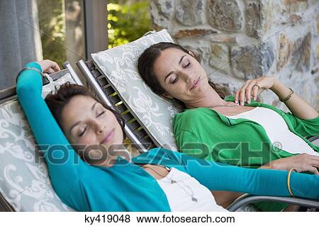 Two women relaxing on lounge chairs View Large Photo Image Stock Photo - Two women relaxing on lounge chairs. Fotosearch